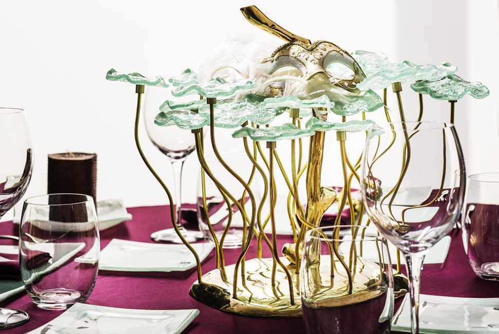 Mint green festive table centerpiece with glass flowers with bronze stems on a purple tablecloth for Mardi Gras