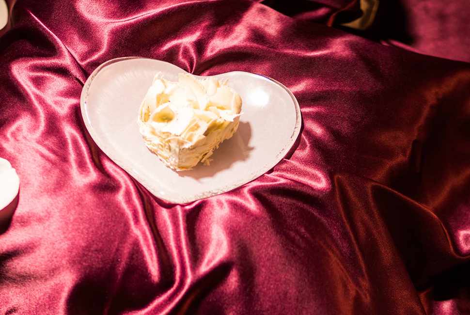 Sweet Valentine romantic dessert heart plate on a red satin sheets with a pretty white coconut cake