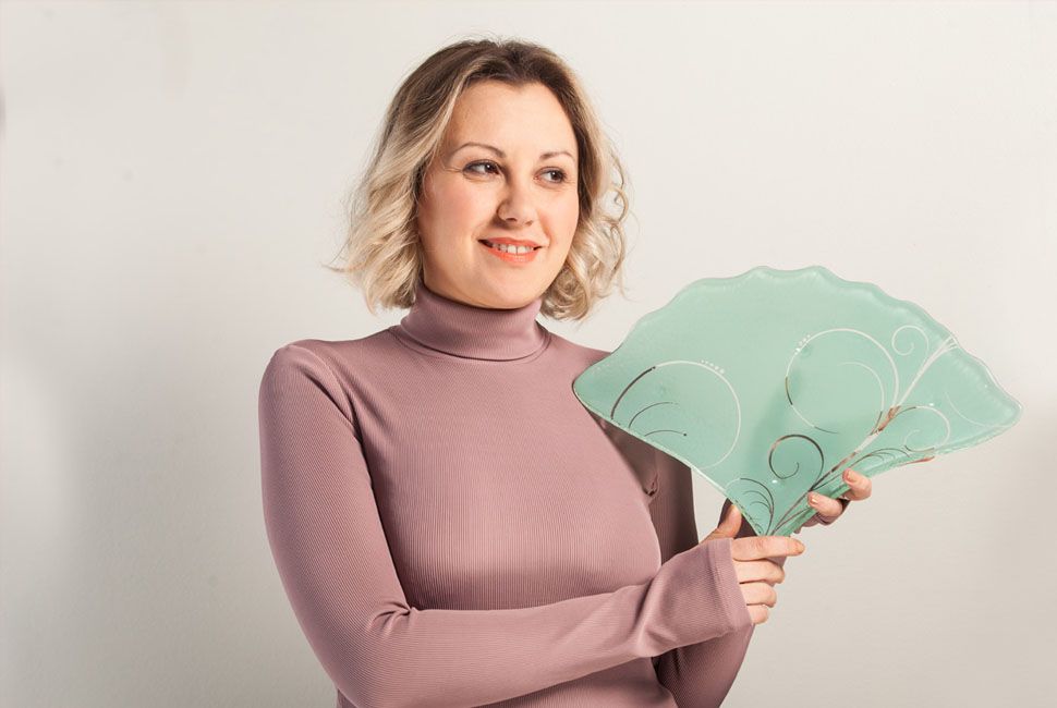 Blond woman with short curled hair holding a mint green fan-shaped tapas plate like a fan.