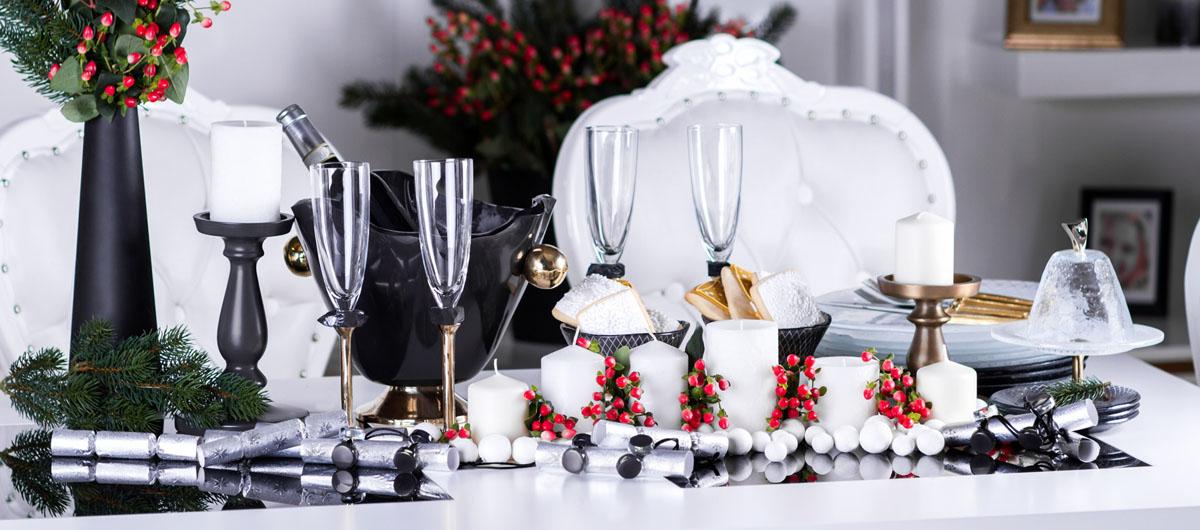 Christmas in July navy blue table setting with navy blue dinnerware and gold champagne glasses with white linen and pearls and Christmas decoration.