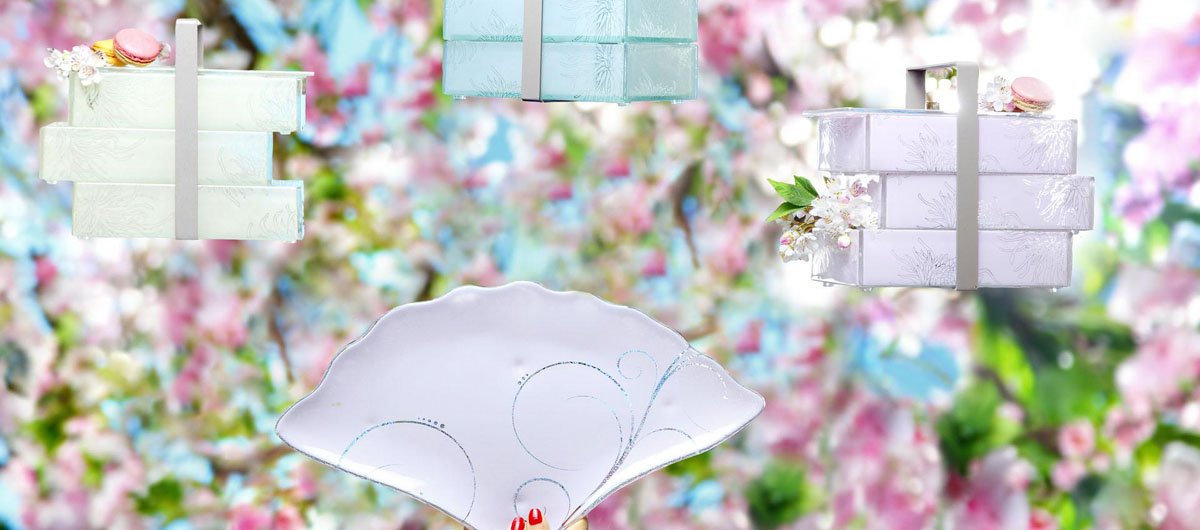3 beautiful glass bento boxes in soft beige, light blue and pastel pink with cherry blossom branches on the background