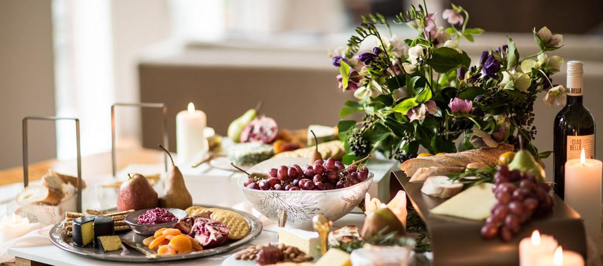 Beautiful table with fruits, cheese and crackers on glass cheese platters and cheese trays.