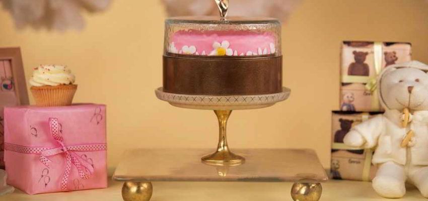 Candy Buffet Ideas WithBeige Cake Serving Board with Pattern and Bronze Supports by Anna Vasily with a Covered Cake Stand and Cake.