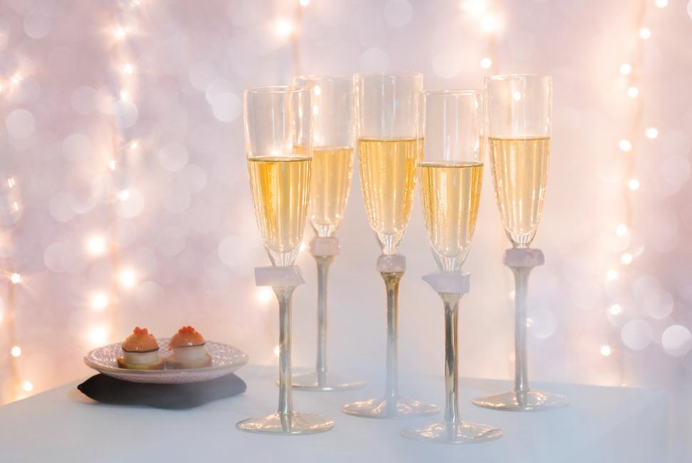 5 gold champagne glasses with bronze stems for new year tableware with a pink background with shimmering lights.