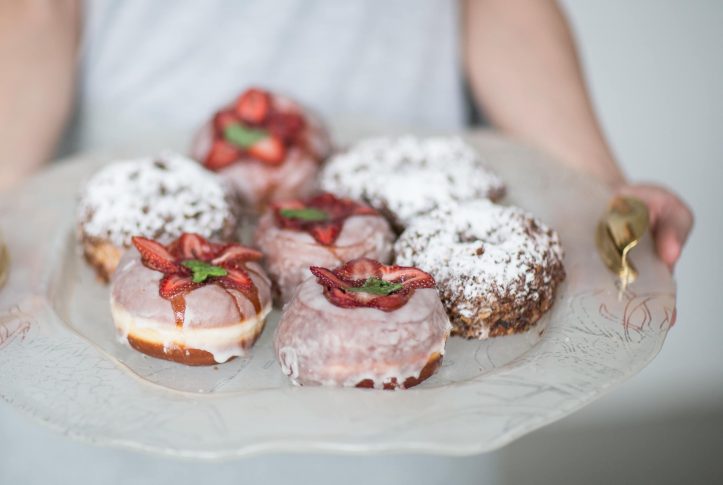 Donut display on a glass tray with bronze handles with strawberry donuts.
