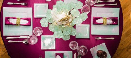 Top view of a festive purple table with mint green dinnerware and a centerpiece decorated with a carnival mask for Mardi Gras by AnnaVasily