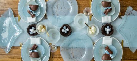A beautiful blue tablescape covered in blue plates chocolate eggs, and other Easter decorations.